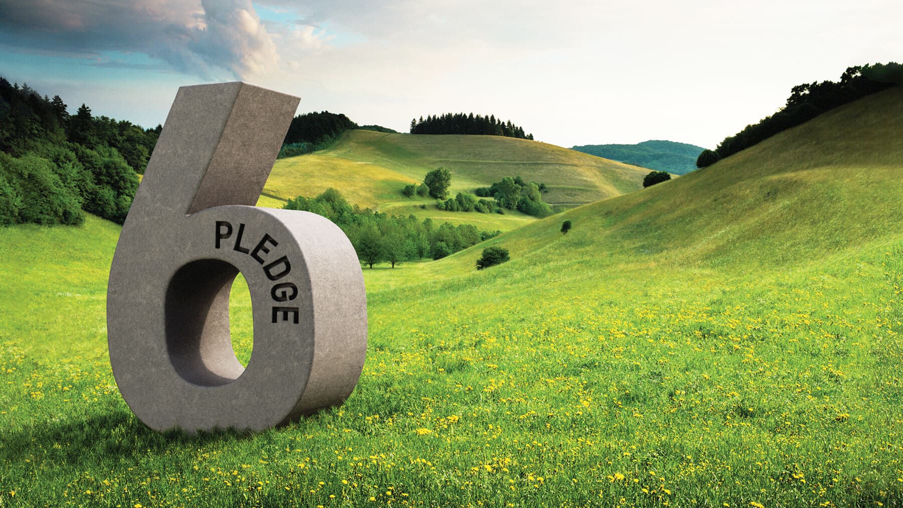 Large gray stone sculpture of the number 6 with 'PLEDGE' along the inner arc, in a sunny green meadow with rolling hills and trees.