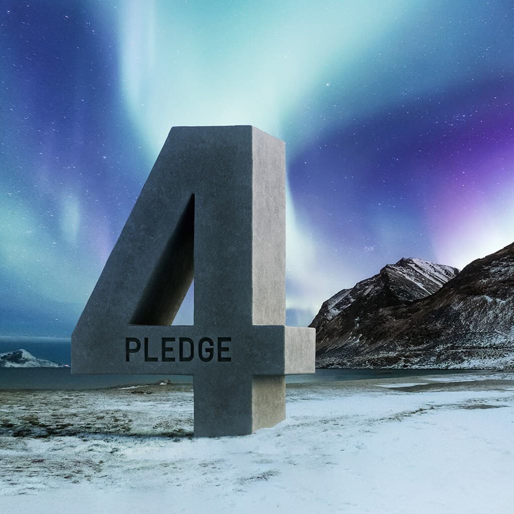 A large gray concrete numeral 4 with the word PLEDGE on its base stands in a snow-covered landscape as the aurora borealis lights the night sky over mountains.