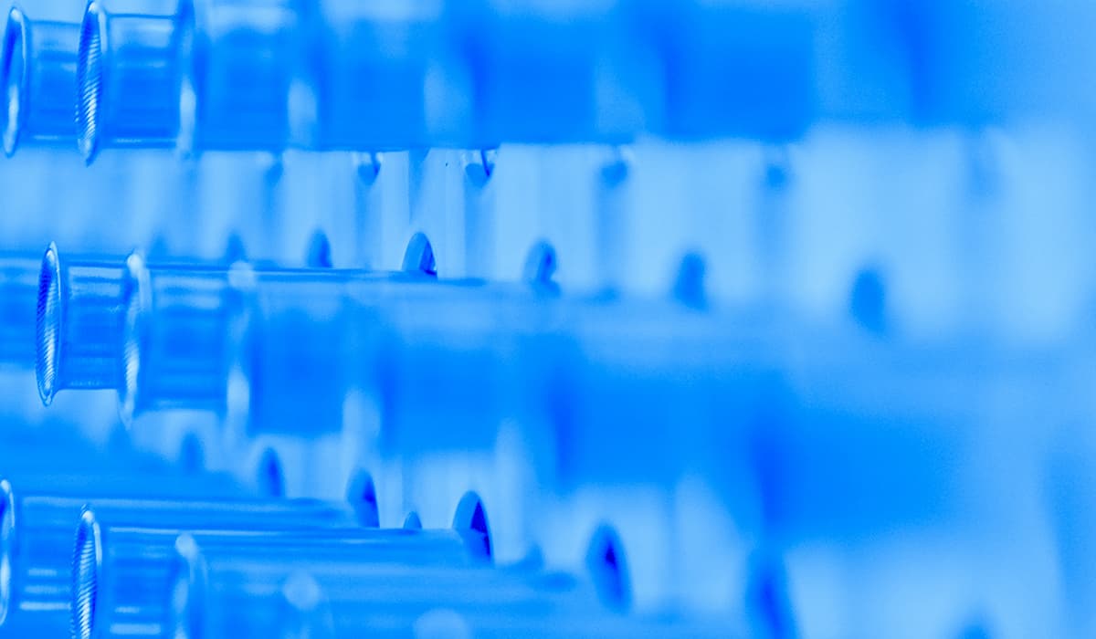 Rangées de tubes en plastique bleus dans un rack de laboratoire, avec une faible profondeur de champ et une teinte bleue dominante.