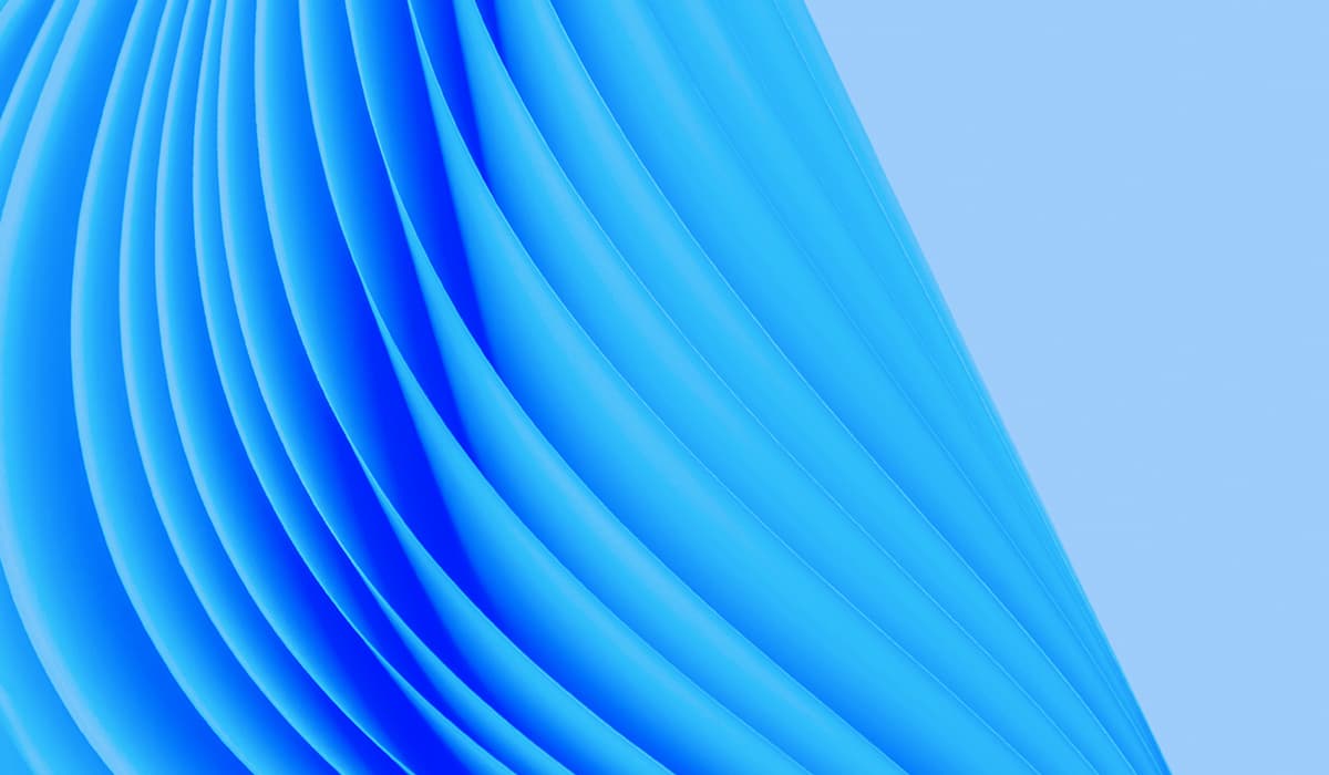 Close-up of vivid blue pleated folds curving diagonally across the frame against a pale blue background.