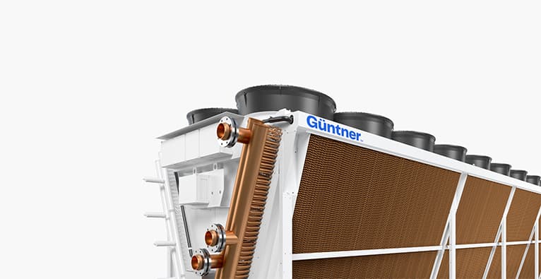 Gran equipo de enfriamiento industrial con aletas de cobre y varios ventiladores en la parte superior sobre una estructura metálica blanca.