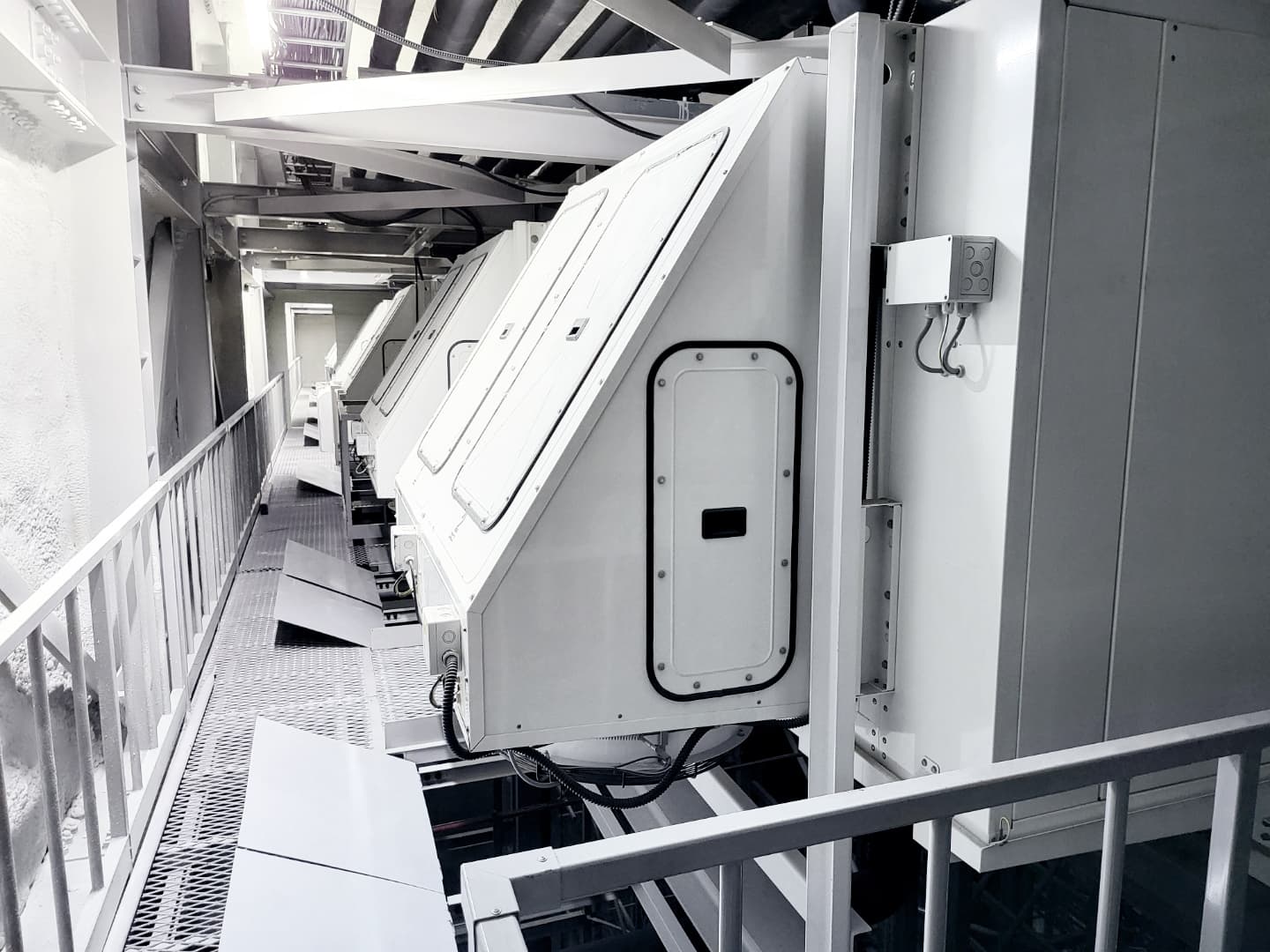 Ausgedehnte industriell wirkende Anlage mit schräg stehenden weißen Reaktoreinheiten oder Containern, umgeben von Metallrahmen, Leitungen und einer Metallplattform.