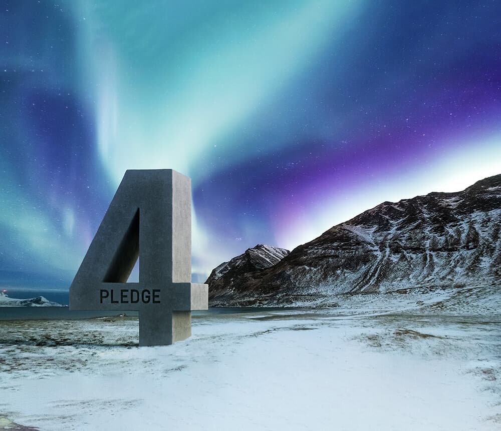 A large concrete number 4 with the word PLEDGE carved on its side stands on a snowy plain, with snow-capped mountains and an aurora-filled night sky.