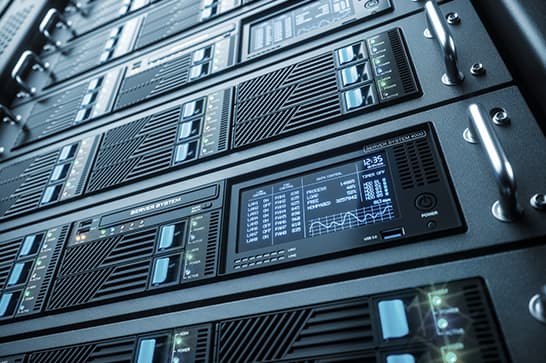 Close-up of stacked server blades with digital readouts and blue indicator lights in a data center.