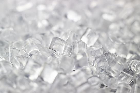 Close-up of many small, clear plastic pieces scattered together, forming a sparkling translucent pile.