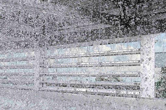 ガラス窓に大量の水滴がついており、透けて見える背後には横長の格子状フェンスがある景色。